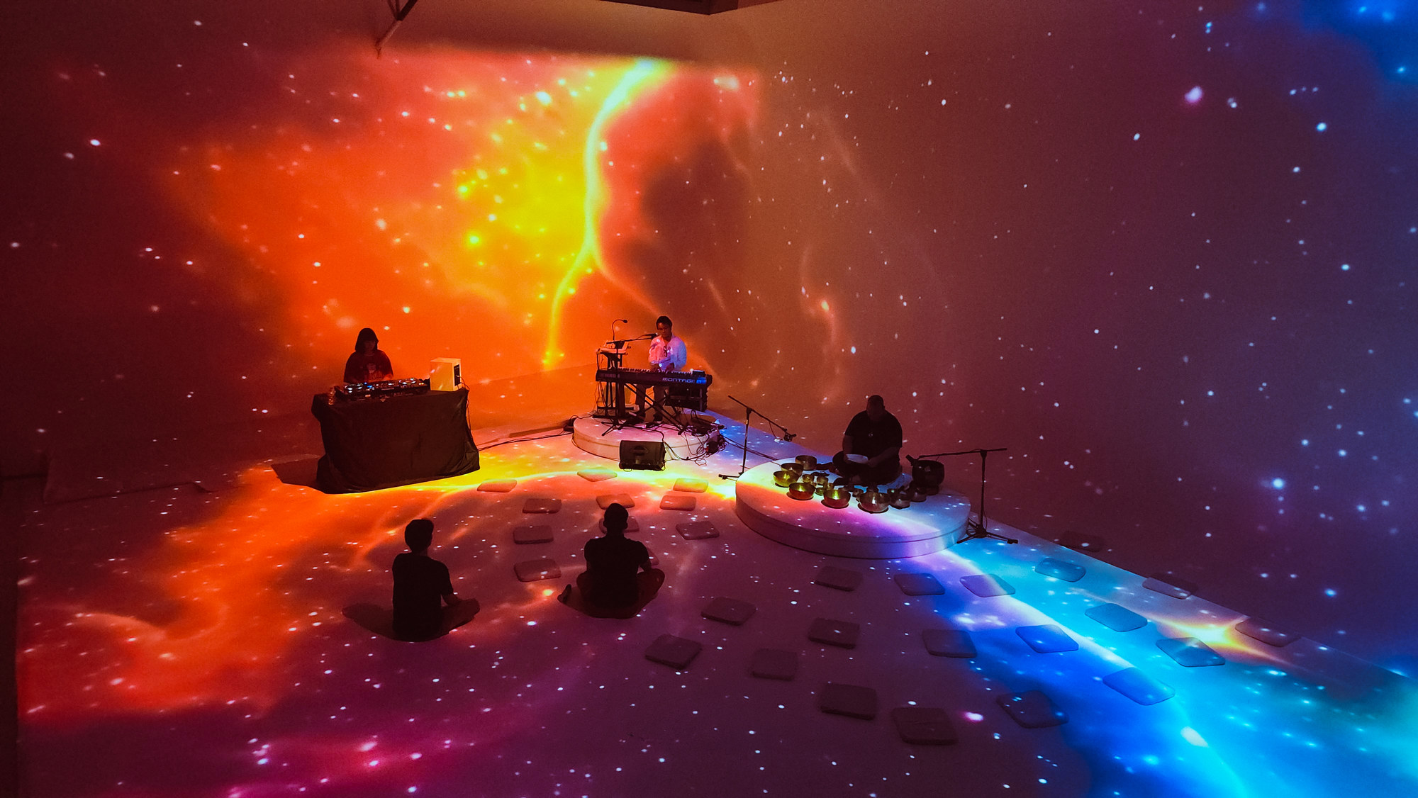 IMMERSIVE STAGE ภาพฉายสีส้มและน้ำเงินบนผนังและพื้น พร้อมผู้ร่วมกิจกรรม