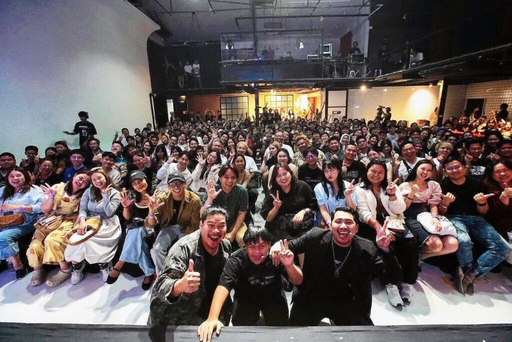 ผู้ร่วมกิจกรรมนั่งฟังด้านหน้าเวทีในฮอลล์แสงโทนม่วง