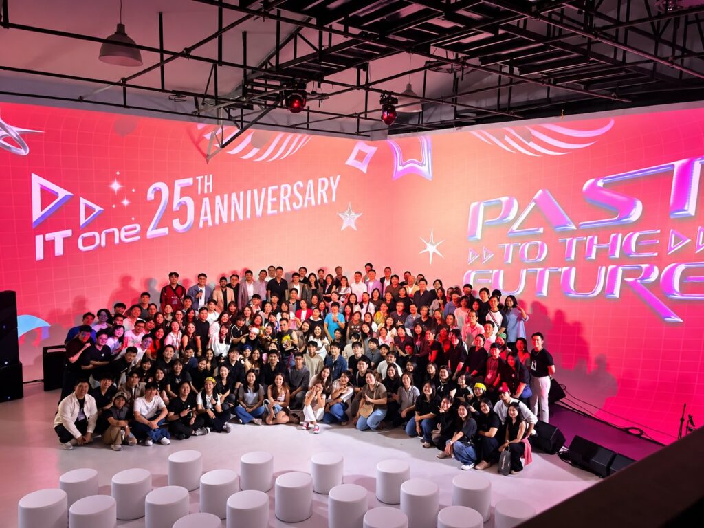 ทีมงานถ่ายภาพร่วมกันหน้าเวทีงานครบรอบพร้อมภาพฉายสีแดง