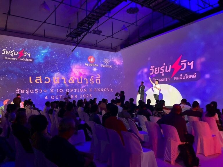ผู้พูดบนเวทีเสวนาและผู้ฟังหน้าภาพฉายสีน้ำเงินม่วง