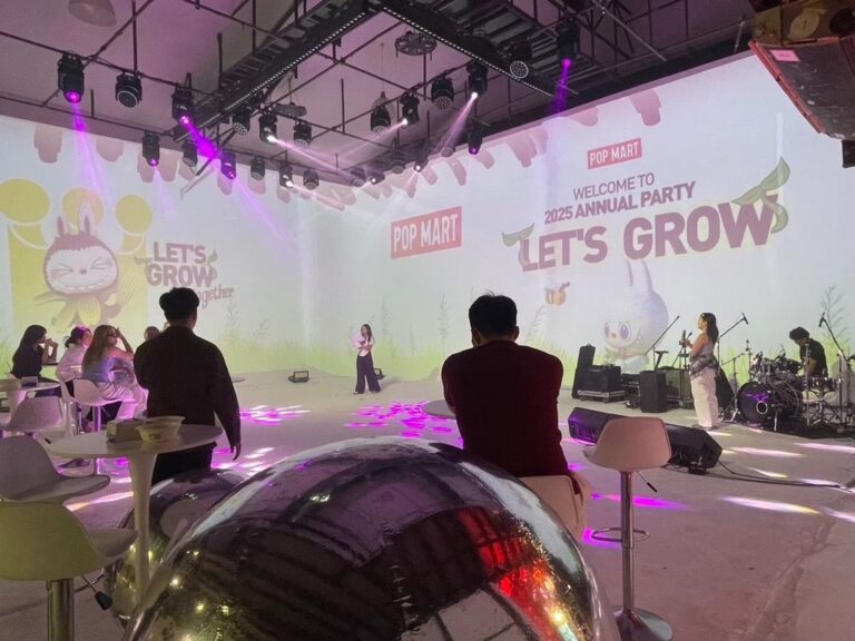 ผู้ร่วมงานนั่งโต๊ะชมการแสดงในงานบริษัทพร้อมภาพฉายสีอ่อน