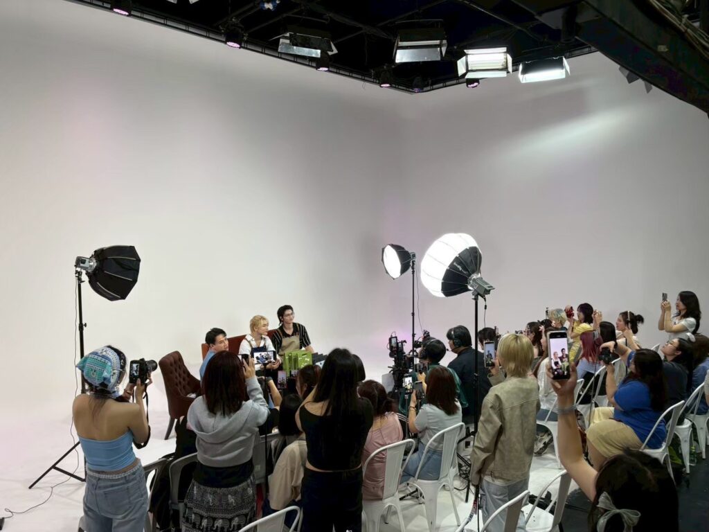 ผู้ร่วมกิจกรรมถ่ายภาพด้วยโทรศัพท์ในสตูดิโอฉากขาว