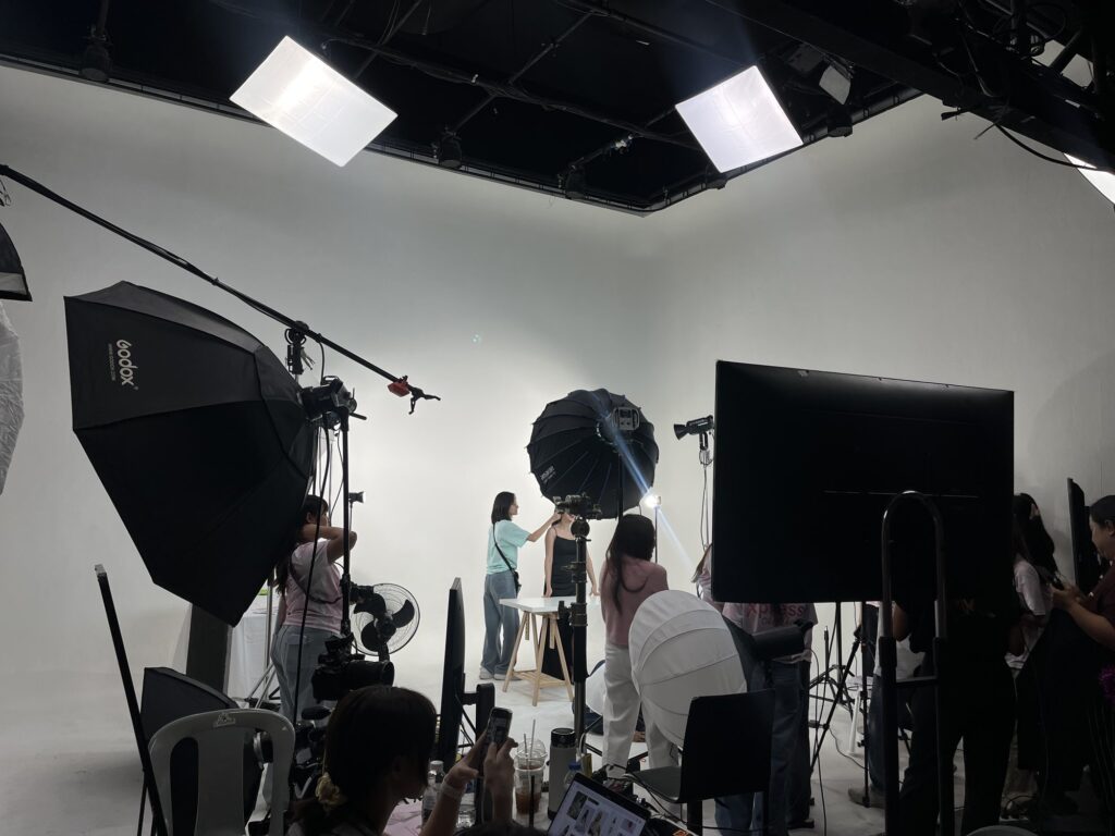 ทีมโปรดักชั่นทำงานในสตูดิโอฉากขาวพร้อมกล้องและไฟ