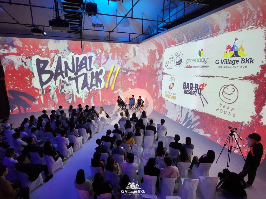 มุมกว้างของเวทีเสวนาและที่นั่งหน้าภาพฉายสีแดงขาว
